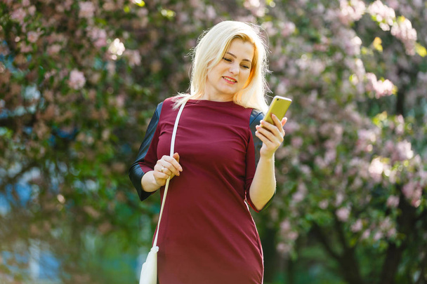 portrait de jeune femme blonde en utilisant smartphone au printemps floraison parc
 - Photo, image