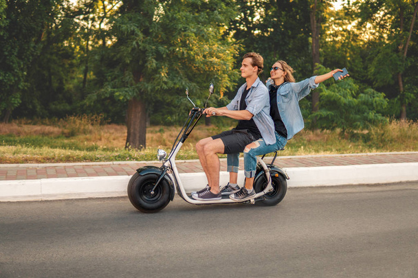 Szép fiatal pár vezetés elektromos kerékpár, nyáron - Fotó, kép