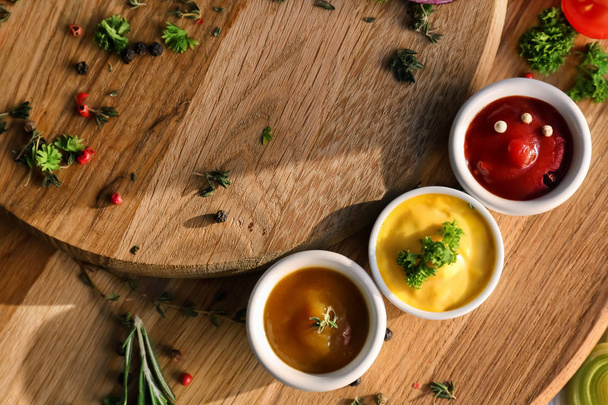 Different tasty sauces in bowls on wooden boards - Photo, image
