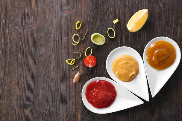 Ahşap masa üzerinde farklı lezzetli soslar ile plakalar - Fotoğraf, Görsel