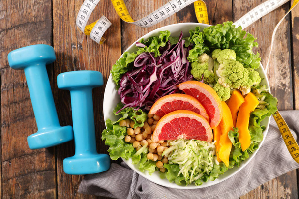 Healthy food concept, mixed vegetarian salad, centimeter tape and dumbbells - Foto, immagini