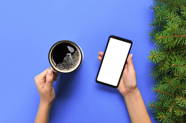 Kobiece ręce trzymając czarny telefon komórkowy z pusty biały ekran i kubek kawy. Makieta obrazu z miejsca kopii. Widok z góry na fioletowy ackground, płaskie leżał. - Zdjęcie, obraz