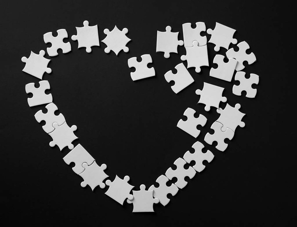 Heart made of jigsaw puzzle pieces on dark background - Zdjęcie, obraz