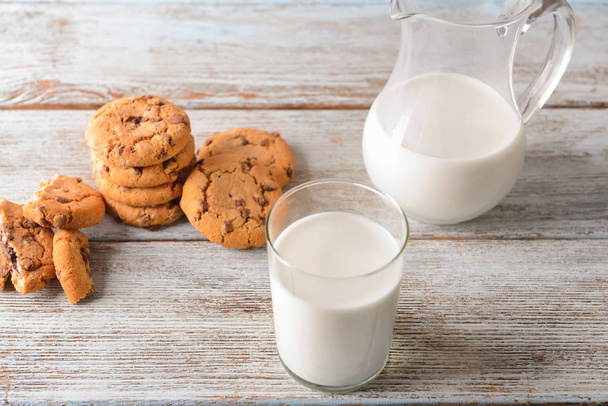 Pliki cookie, szkło i Dzbanek mleka smaczne na drewnianym stole - Zdjęcie, obraz
