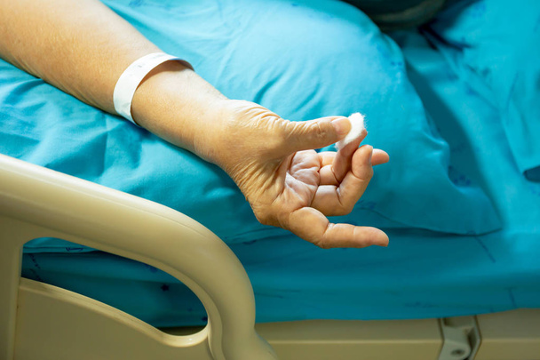 Senior patiënt met behulp van katoen, wol stop bloed bloeden uit een vinger - Foto, afbeelding