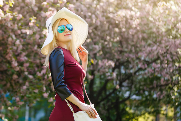 portrait of young blonde woman posing in blooming spring park - Photo, Image
