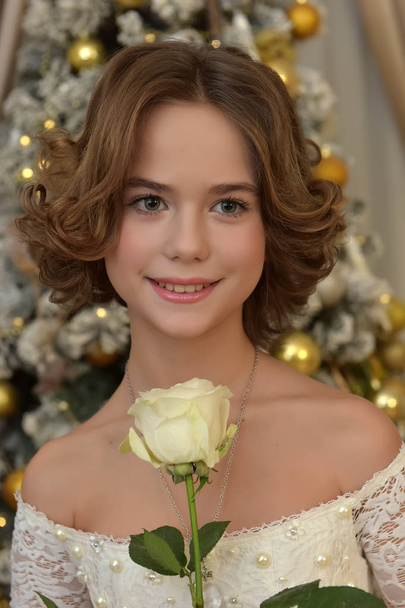 beautiful girl in white dress with white rose in hands in christmas - Foto, Imagem