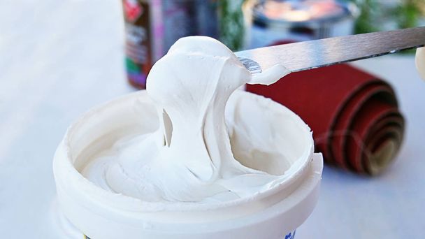 White acrylic glazing putty for wood and metal, interior and exterior use on a putty knife showing the paste consistency. - Фото, изображение