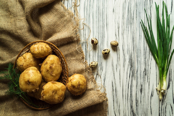 πατάτες, κρεμμύδια, αυγά ορτυκιών, χόρτα σε ένα λευκό ξύλινο τραπέζι - Φωτογραφία, εικόνα