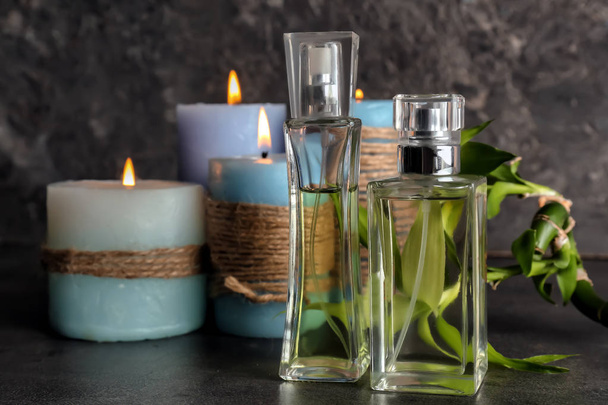 Пляшки парфумів з палаючими свічками на столі
 - Фото, зображення