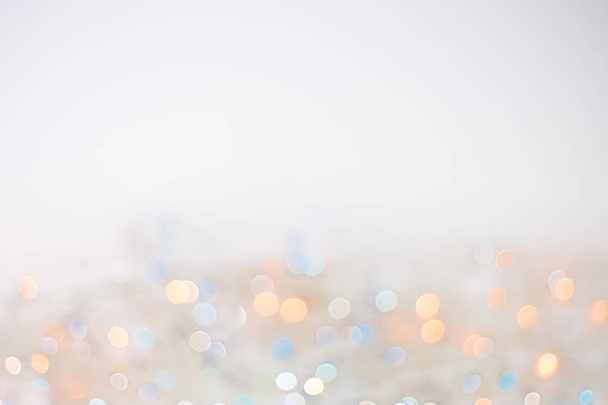 Festive New-year background with bokeh from Christmas lights glowing. White, blue, yellow blurred lights - 写真・画像
