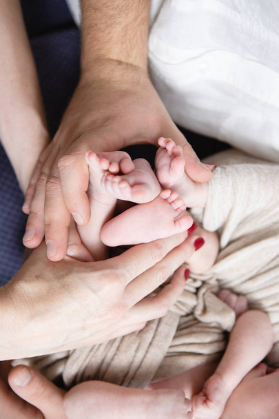 Pies de bebés en las manos de los padres
 - Foto, imagen