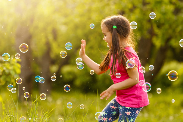 Chica alegre jugando con burbujas de jabón en el jardín verde
 - Foto, Imagen