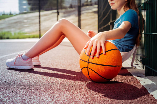 Relaxed teenager sitting on floor with ball - Foto, Imagen