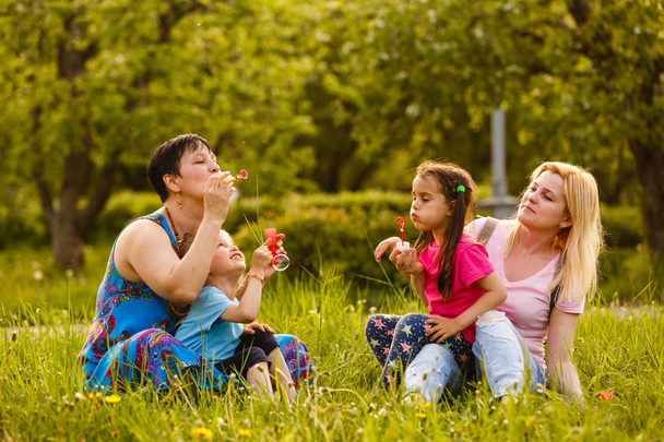 Μητέρες με κόρες που ανατινάζουν φυσαλίδες σαπούνι στο πράσινο πάρκο - Φωτογραφία, εικόνα