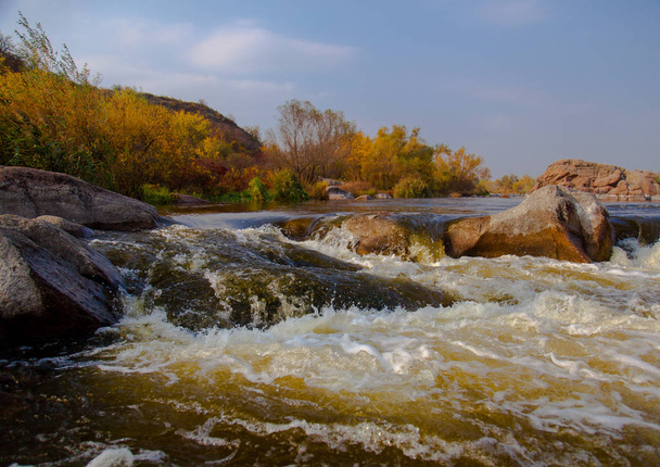 piedra en un río rápido en otoño árboles amarillos en la orilla
 - Foto, imagen