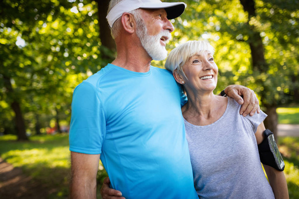 Happy senior couple staying fit by exercise jogging - Valokuva, kuva