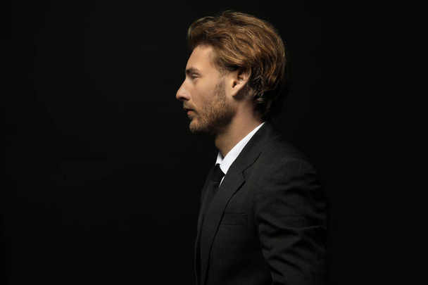 Portrait of handsome businessman in profile against black background - Foto, Imagem