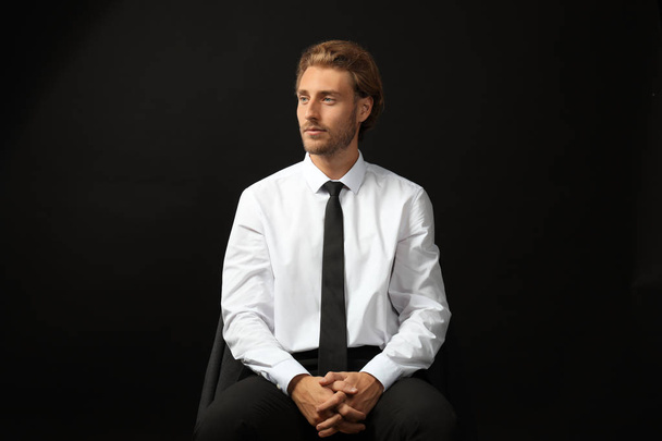 Uomo d'affari di successo seduto sullo sfondo nero
 - Foto, immagini