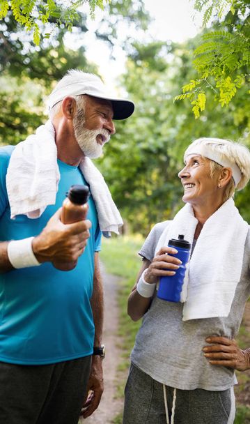 Fitness, sport and lifestyle concept - happy senior couple in sports clothes outdoors - Photo, image