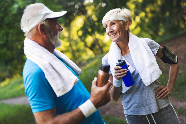 Senior couple jogging and running outdoors in park nature - Foto, afbeelding