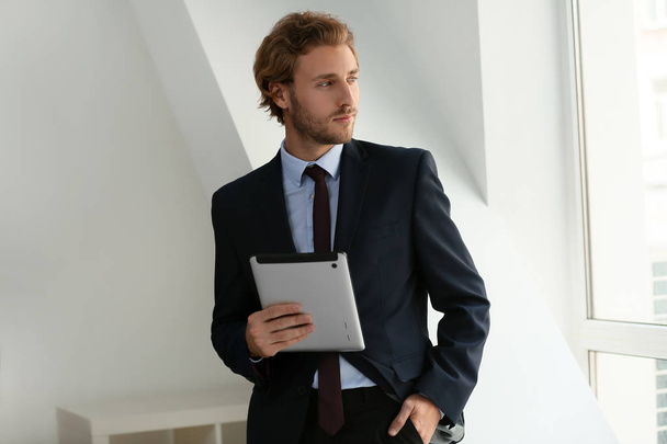 Successful businessman with tablet computer near window - Foto, imagen