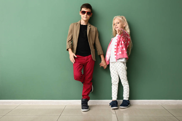 Söpö poika ja tyttö muodikkaissa vaatteissa lähellä väriseinää
 - Valokuva, kuva