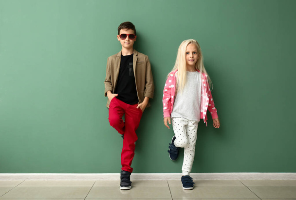 Χαριτωμένο αγόρι και κορίτσι σε μοντέρνα ρούχα κοντά σε χρώμα τοίχου - Φωτογραφία, εικόνα