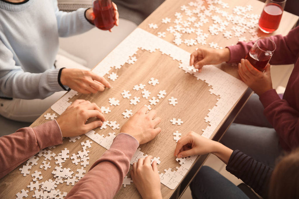木製テーブルの上のパズルを組み立てる人のグループ - 写真・画像