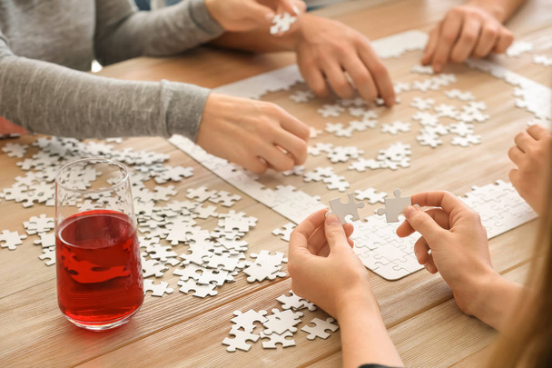 Gruppe von Menschen montiert Puzzle auf Holztisch - Foto, Bild