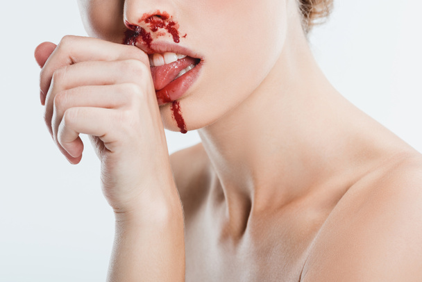 primo piano di donna nuda con lesioni sul viso leccare il sangue dalla mano isolata su bianco
 - Foto, immagini