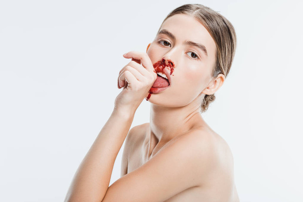 mujer desnuda con lesión en la cara lamer sangre de la mano aislada en blanco
 - Foto, Imagen