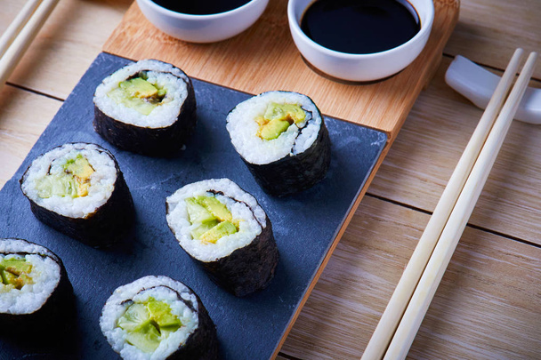 Rollos veganos de sushi hechos con algas nori, arroz de sushi, pepinos y aguacate
 - Foto, imagen