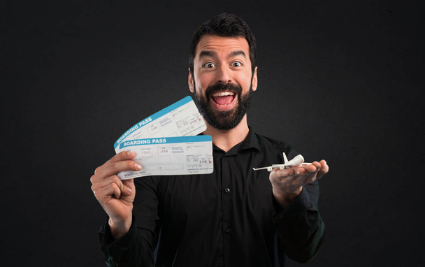 Handsome man with beard holding air tickets on black background - Photo, Image