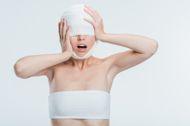 vyděšená žena s obvazy dotýkat hlavy izolované na bílém - Fotografie, Obrázek