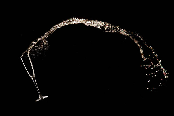 Goblet with champagne wine splashing out, isolated on black background. Celebration and New Year concept - Foto, Imagen