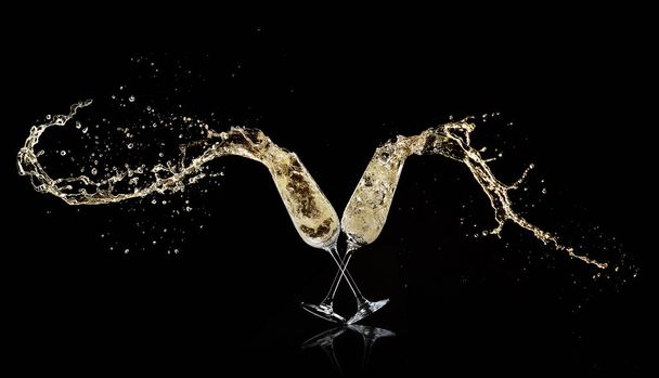 Goblets with champagne wine splashing out, isolated on black background. Celebration and New Year concept - Foto, Bild