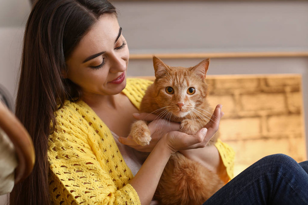 Woman with cute cat resting near fireplace - Photo, image