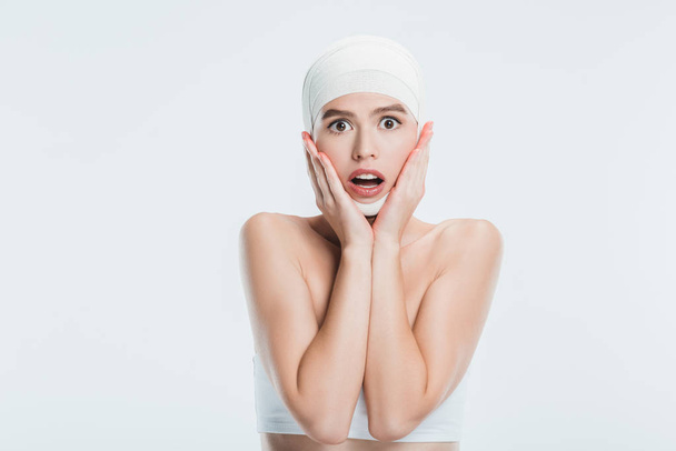 scared woman with bandages over head after plastic surgery isolated on white - Foto, Imagem
