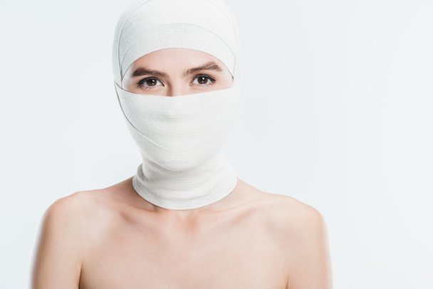 κοντινό πλάνο της γυμνή γυναίκα με λευκό Επίδεσμοι πέρα από το πρόσωπο και το κεφάλι που απομονώνονται σε λευκό - Φωτογραφία, εικόνα