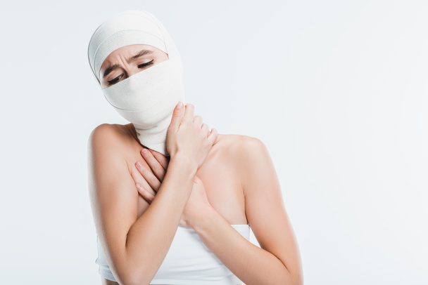 painful woman with white bandages over face and head isolated on white - Foto, immagini