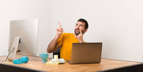 Чоловік працює з ноутбуком в офісі, вказуючи пальцем індексу і дивлячись вгору
 - Фото, зображення