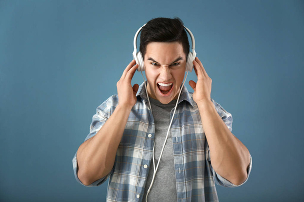 emotionaler junger Mann hört Musik auf farbigem Hintergrund - Foto, Bild
