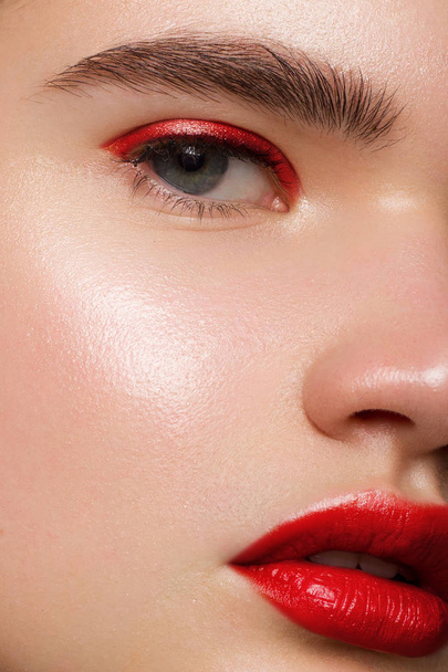 Closeup of beauty woman with clean shiny skin and bright makeup. Fashion, spa, cosmetology, injections into red lips, shadows on brown eyes and thick eyebrows, cosmetics, makeup, beautiful - Foto, afbeelding