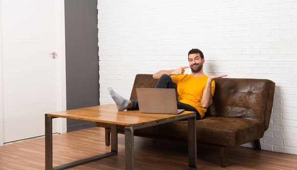 Człowiek z laptopem w pokoju trzymając miejsce wyobraźni na dłoni do wstawienia reklamy - Zdjęcie, obraz