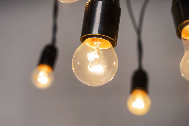 Glowing light bulbs on grey background - Foto, imagen