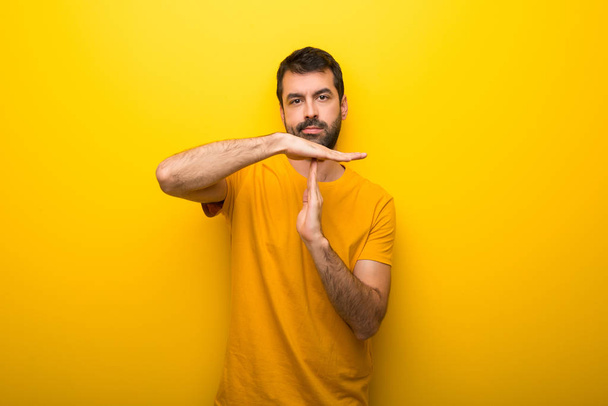 Homem na cor amarela vibrante isolado fazendo parar gesto com a mão para parar um ato
 - Foto, Imagem