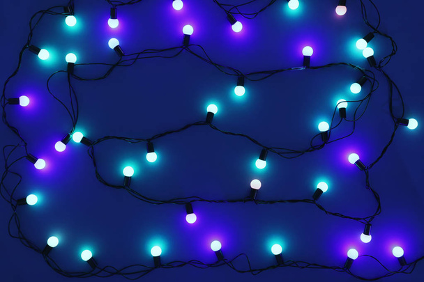 Christmas lights on blue background, top view - Foto, Imagen