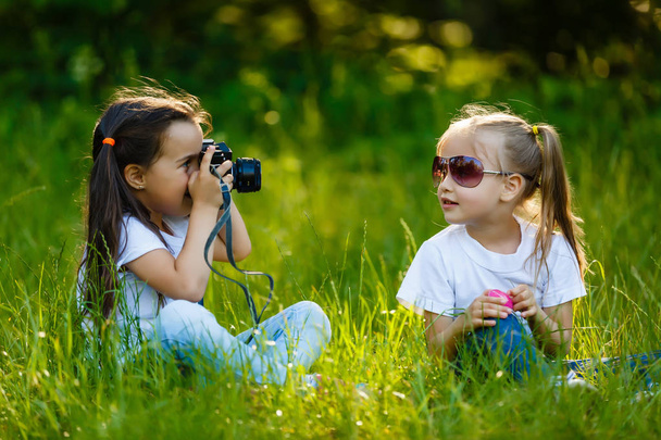 Twee kinderen meisje houdt van camera en nemen in groen park - Foto, afbeelding