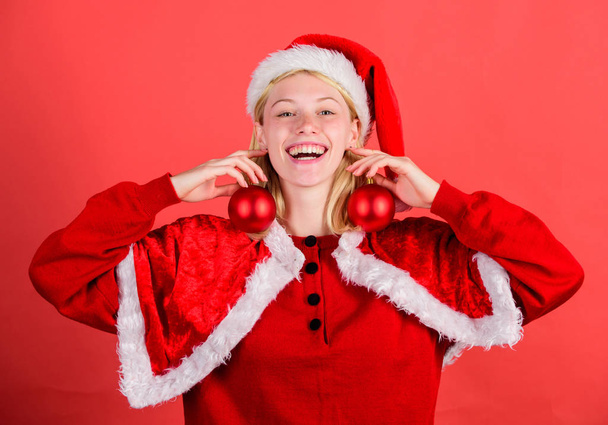Christmas fun. Enjoy celebration with costume and decor. Girl happy wear santa costume celebrate christmas hold ball decor red background. Christmas preparation concept. Favorite time year christmas - Photo, image